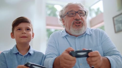 Boy and Senior Man Gaming Together at Home