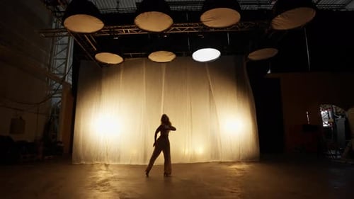Silhouette of a Professional Dancer Performing in Studio in Soft Warm Lighting