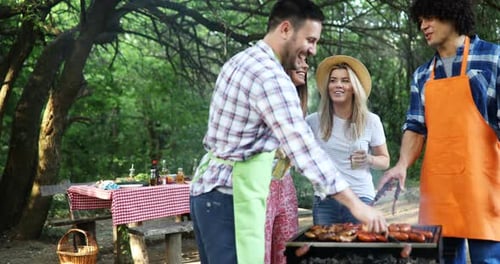 Friends Enjoy Barbecue at Picnic in Wooded Area