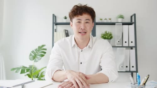Man in White Shirt Talking at Desk