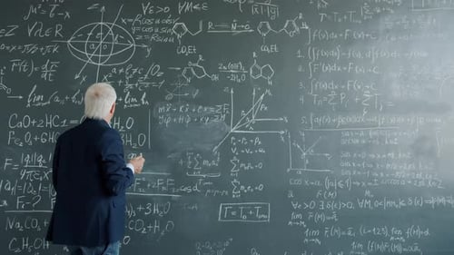 Intelligent Professor Working at Project in College Writing Formulas on Chalkboard Wall