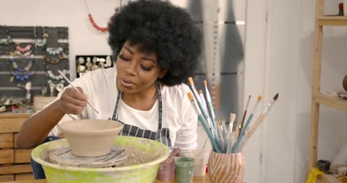 Young Black Woman Painting a Clay Bowl at Workshop