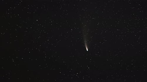 Comet Streaking Across Starry Night Sky