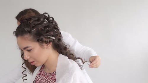 Stylist Curls Woman's Hair with Clips and Hairspray