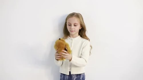 Happy Girl Hugs Stuffed Animal Against White Background
