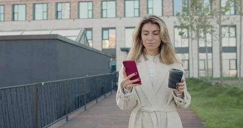 Crop View of Woman with Blond Hair Using Smartphone and Drinking From Paper Coffee Cup. Beautiful