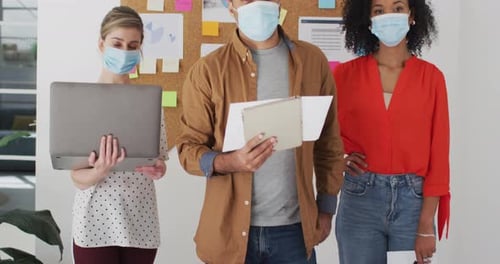 Office colleagues wearing face mask standing in office