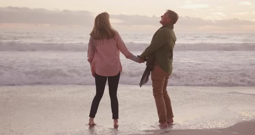 Active senior couple holding hands on beach