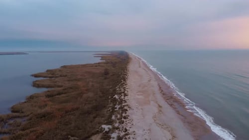 Empty estuary. Sandy beach with big sea waves hitting on seashore.
