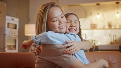 Loving Mother and Daughter Embrace on Sofa