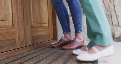 Parte baja de madre e hija que entra a la casa