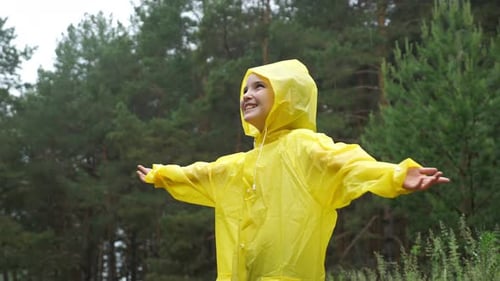 Happy Child in Yellow Raincoat Enjoys the Rain