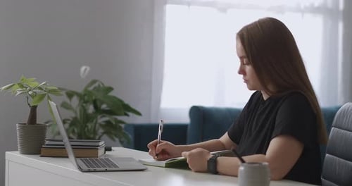 Woman Studying at Desk with Laptop at Home