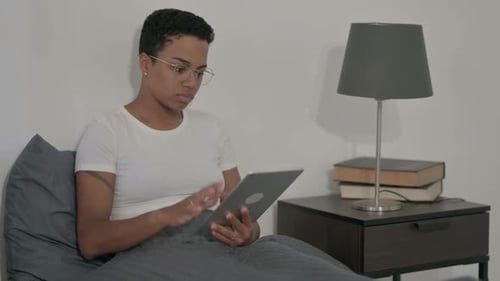Woman Using Tablet in Bed at Home