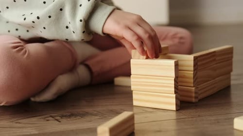Un niño pequeño juega un juego de mesa, el niño construye con bloques de ladrillos de madera.