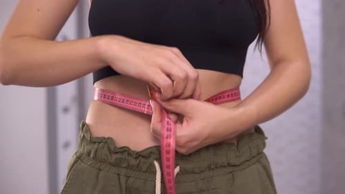 Woman Measuring Waist with Tape Measure Close Up