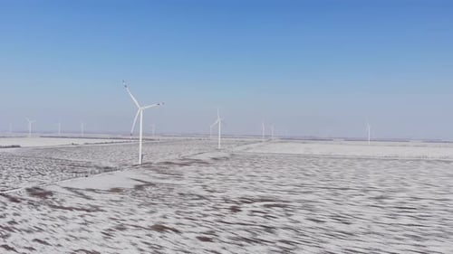 Windmühlen mit Klingen stehen in einem mit Schnee bedeckten Feld
