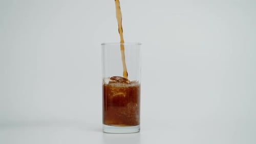 Brown Soda Being Poured into Glass with Ice