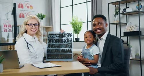 Un homme et sa jolie petite fille qui posent devant la caméra avec une femme médecin