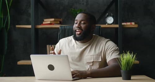 Man Video Conferencing and Smiling Using Laptop Indoors