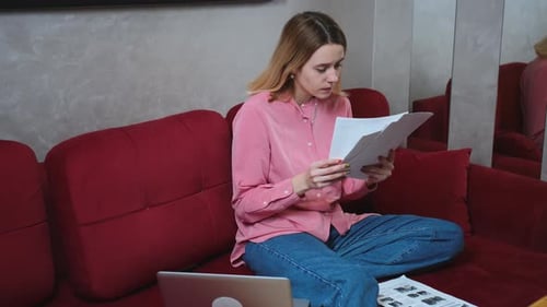 Pretty Caucasian Woman Working with Papers Laptop on Sofa at Home Woman Doing Homework on Sofa with