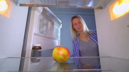 Woman Looks in Refrigerator and Puts Apple Back