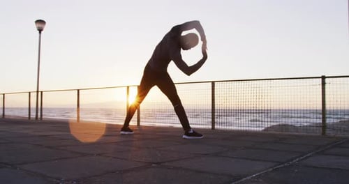 Young Adult Stretching on Boardwalk at Sunrise