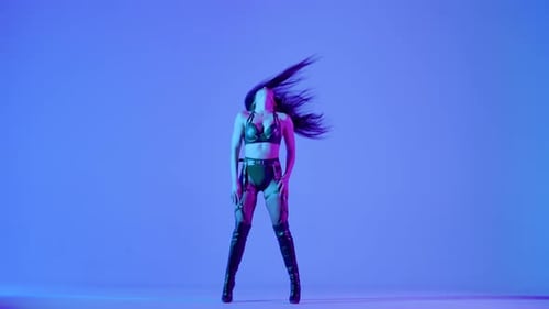 Sexy Brunette in schwarzen Lederunterwäsche tanzt erotisch in einem dunklen Studio, das von Blau beleuchtet wird
