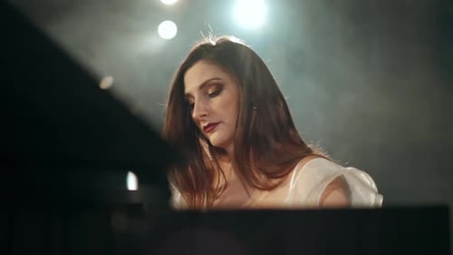 Elegant Woman Plays Piano in Smoky, Spotlit Performance