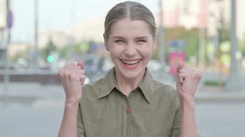 Excited Young Woman Celebrating Success in Urban Setting