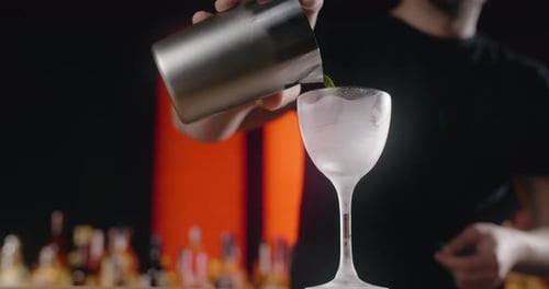 Bartender Pouring Chilled Green Cocktail Into a Glass