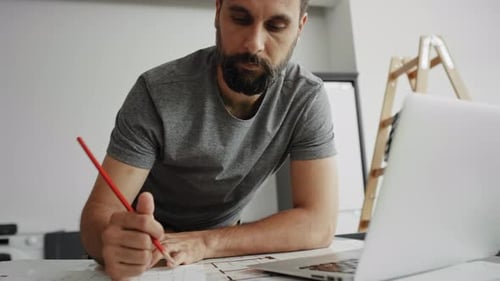 Bearded Man Working at Table on Laptop Computer