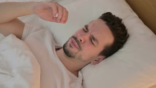 Porträt eines jungen Mannes mit Kopfschmerzen im Bett