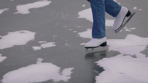 Ice Skating on a Frozen Lake. In the Frame, Close-up of Legs in Jeans and White Skates.