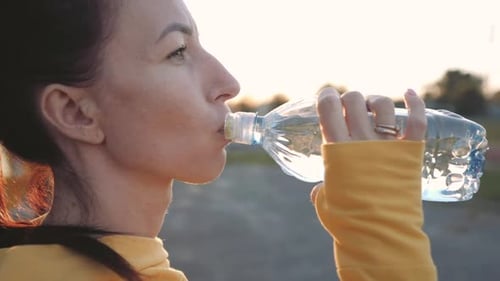 Fitness Young Woman Drinking From Sport Bottle During a Workout Pause in Stadium