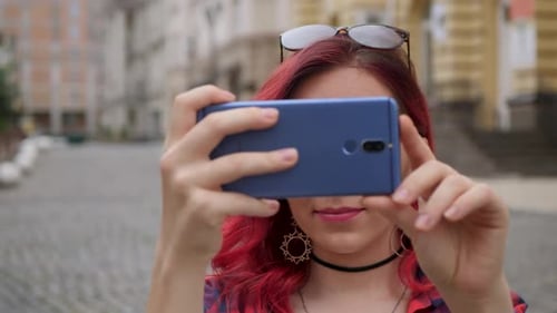Young Woman Taking Photos with Smartphone in City