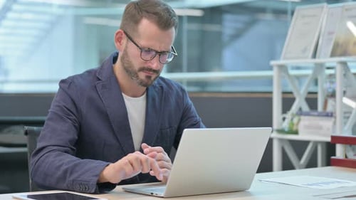 Man Frustrated While Working on Laptop in Office