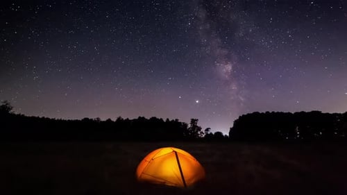 Orange Iluminated Tent in the Forest Under the Starry Sky. Timelapse