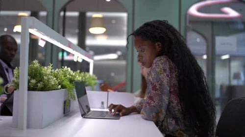 Afro business woman meeting hands using a laptop with stats