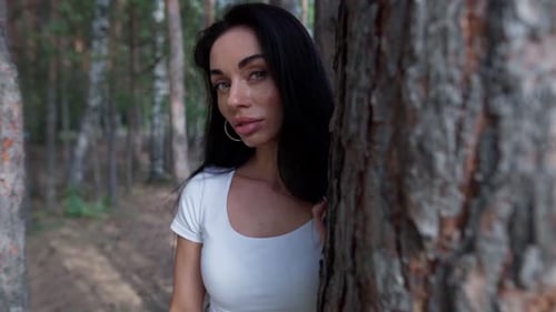 Woman Standing Next To a Tree in a Forest