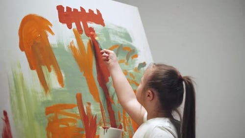 Girl Painting with Orange Paint on Large Canvas