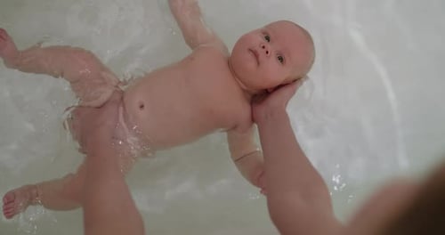 Top View of Funny Newborn Baby Swimming During Bathing