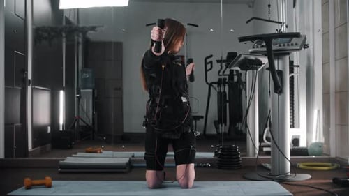 Junge Frau trainiert im Fitnessstudio im Ems Suit