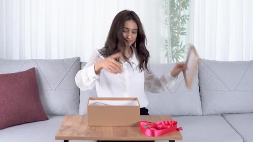 Woman Wrapping Birthday Gift with Pink Ribbon