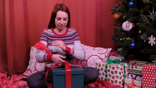 Woman Opens Christmas Gift near Decorated Tree