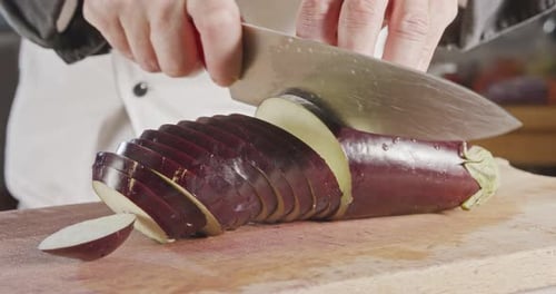 Slow motion close up of a chef knife slicing an Eggplant