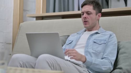 Man Frustrated While Typing on Laptop at Home