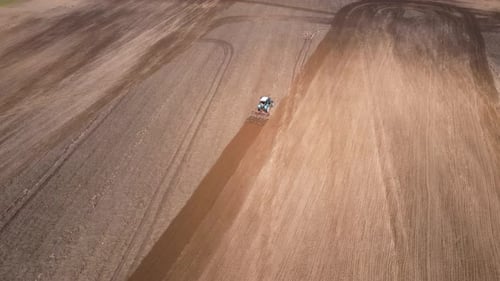Tractor Plows Ground on Cultivated Farm Field