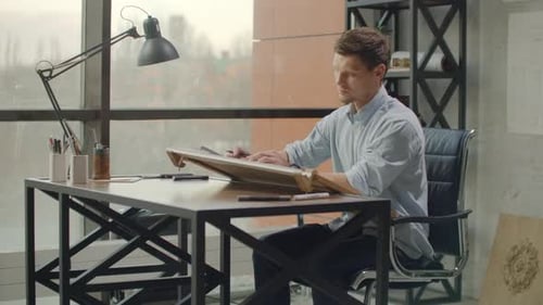 Man Working at Drawing Table in Urban Office