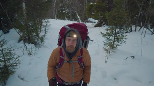 Man Hiking Through Snowy Woods in Winter